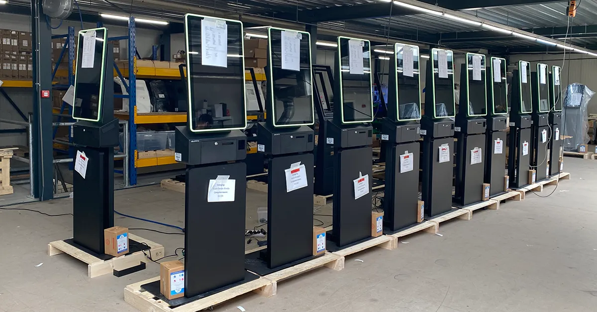 Bestelzuil van HANOS SHOP in de productiehal, ontworpen en geleverd door Prestop, met op maat gemaakte posterplaat en geïntegreerde software.